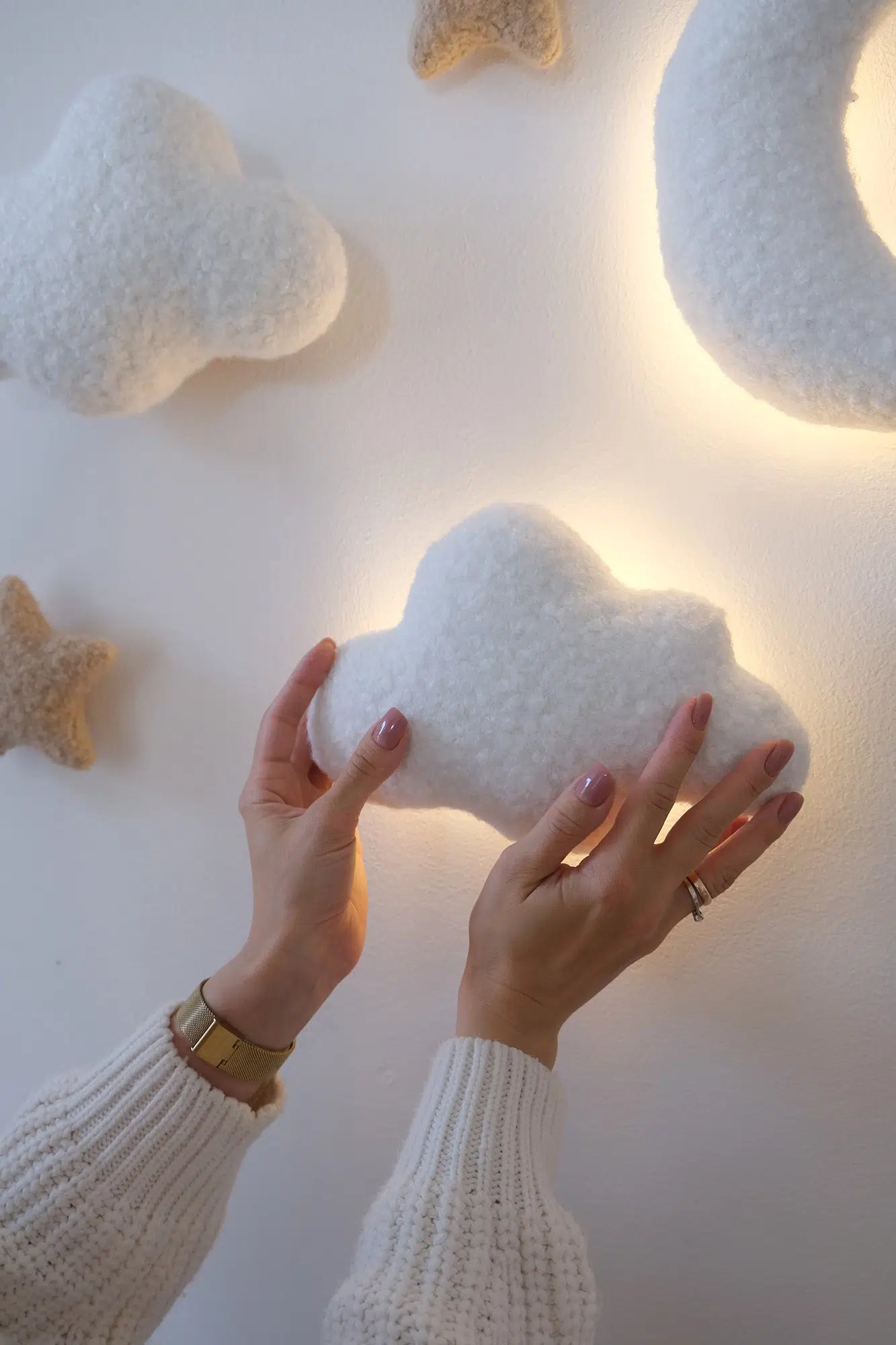Installing boucle cloud night light on nursery wall – hands placing white cloud lamp next to decorative stars, warm LED glow visible