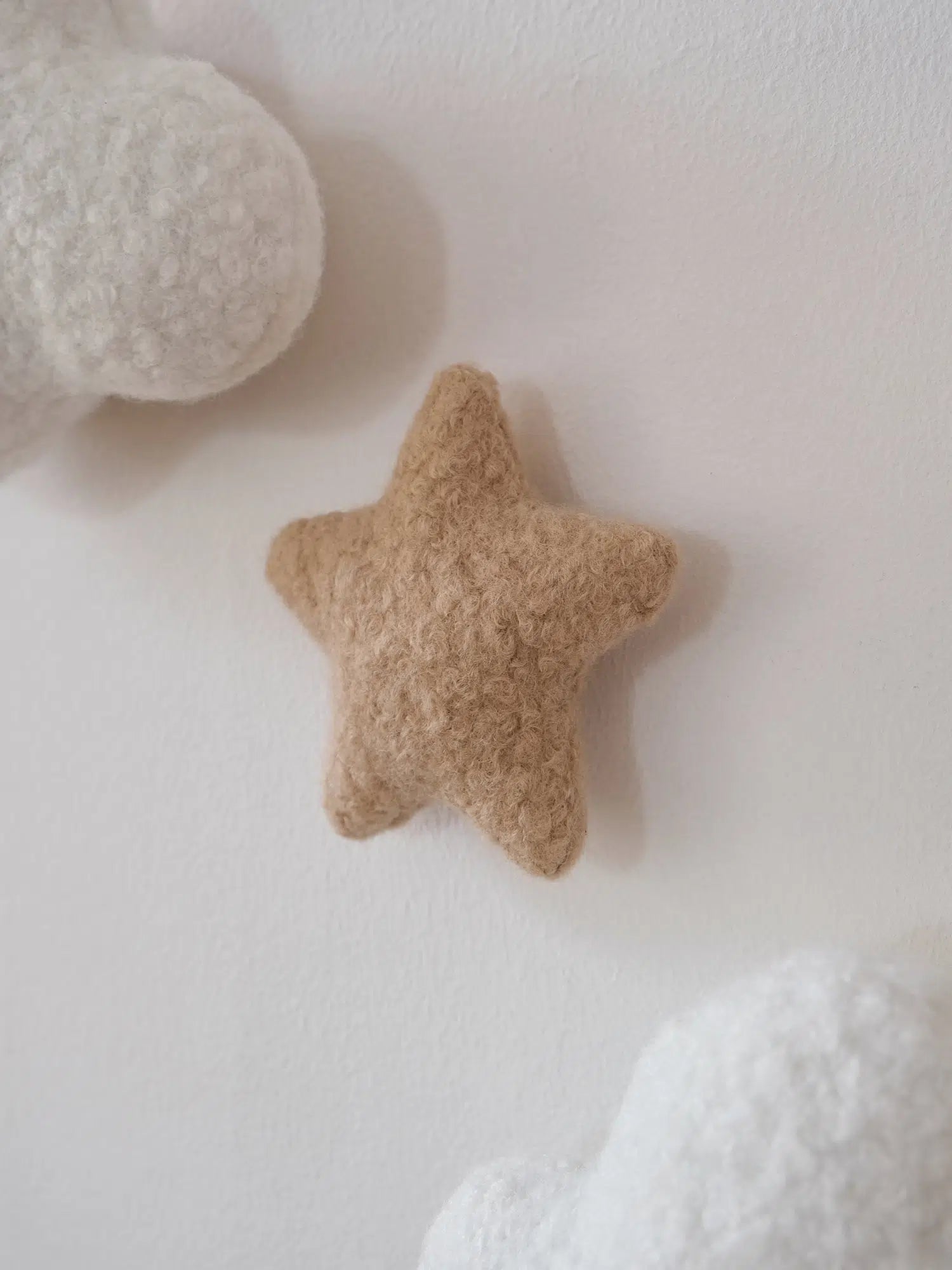 Handmade boucle decorative star wall accent for nursery – close-up of caramel-colored star paired with white cloud night lights