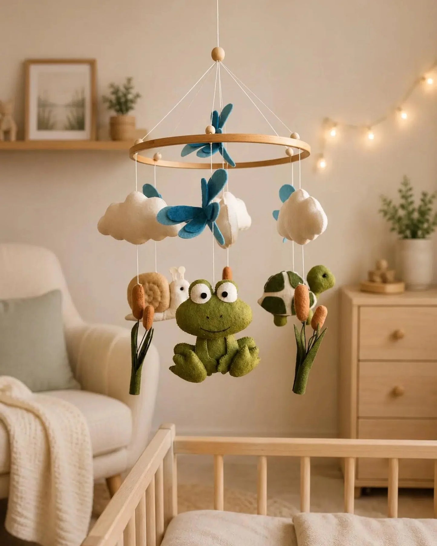 Children's mobile with frogs and clouds hanging above a crib in a nursery.