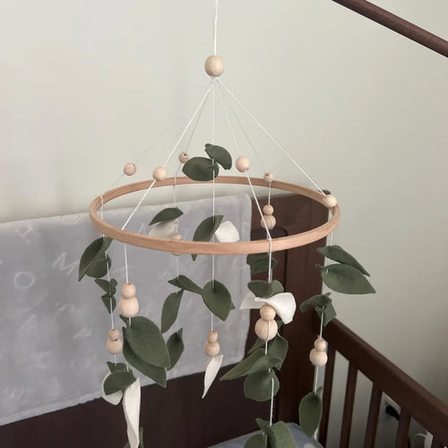 Handmade green leaves mobile over dark wood crib – felt eucalyptus nursery mobile with wooden beads