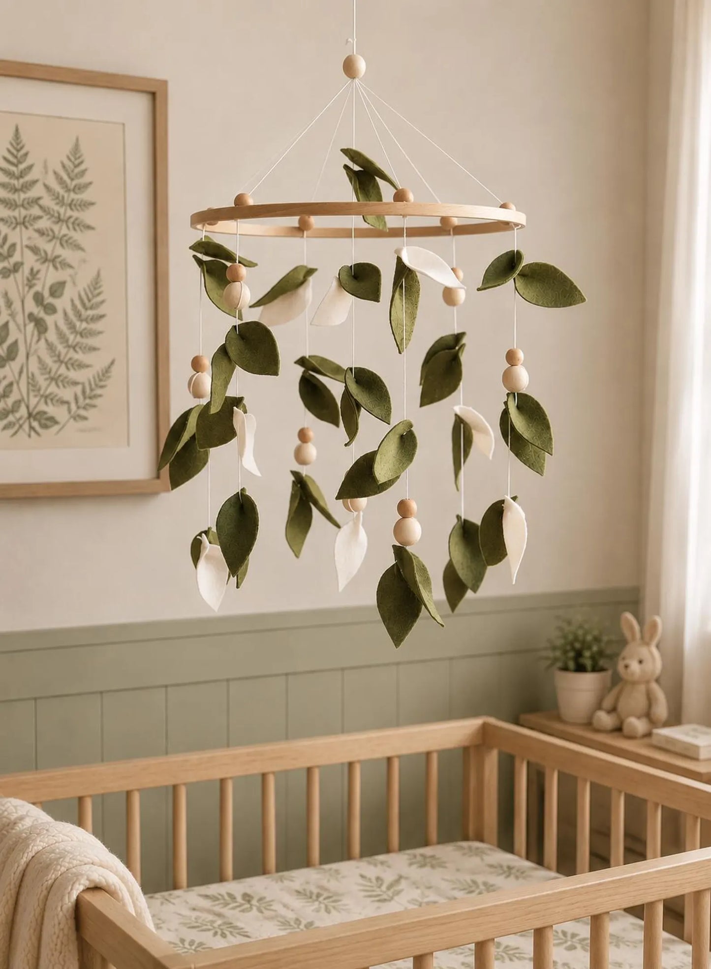 Felt green leaf mobile above crib in botanical nursery – nature baby room decor with fern art