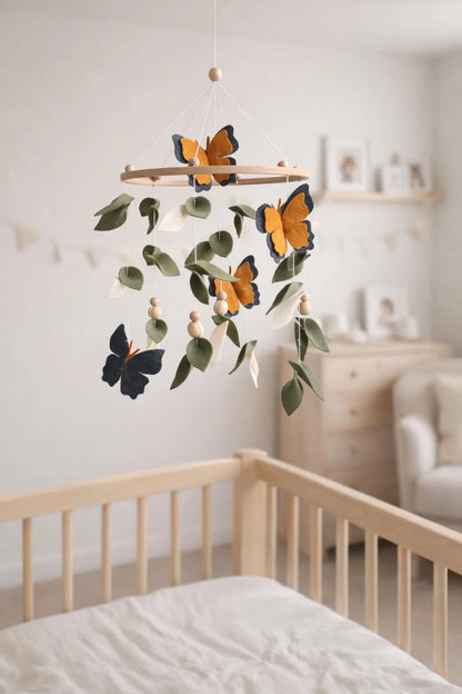 Felt baby mobile with monarch butterflies hanging above crib – nature nursery decor