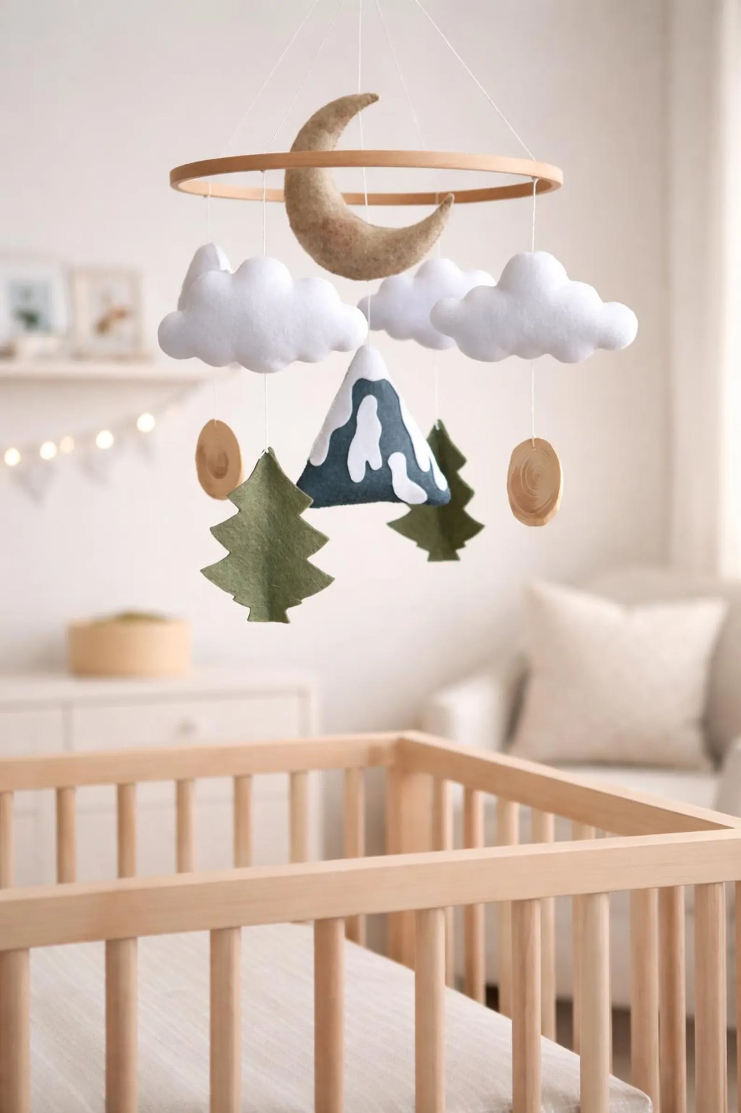 Felt mountain moon mobile above crib in nursery – woodland baby room decor with fairy lights