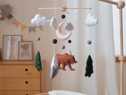 Close-up of a felt bear baby mobile with snowy mountains, fir trees, moon and natural wool balls