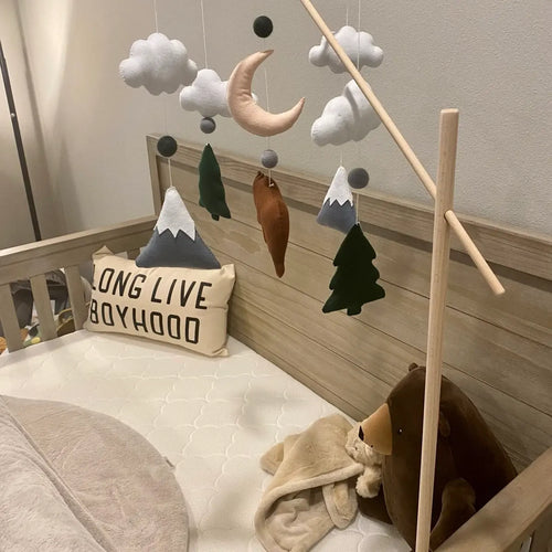 Felt bear woodland crib mobile with moon, clouds and snowy mountains above baby bed