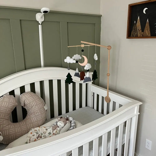 Felt bear mobile with moon, clouds and snowy mountains over white crib