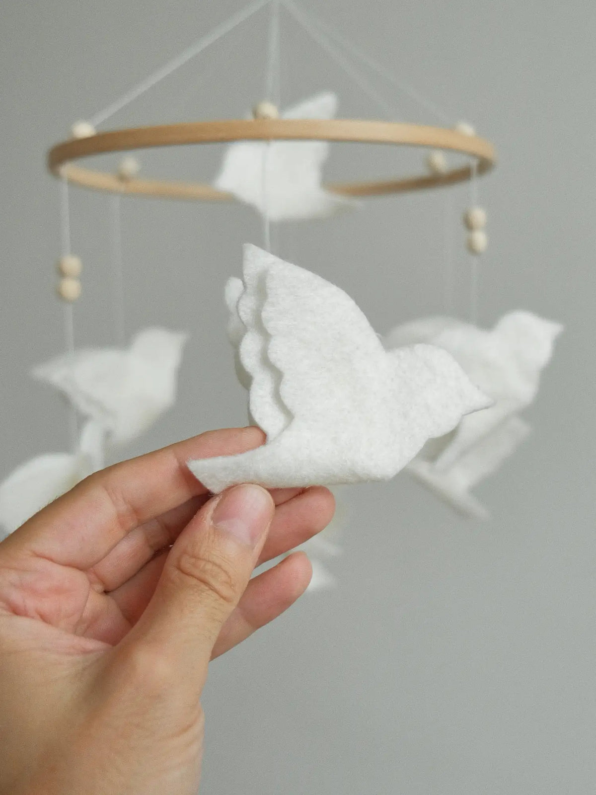 Close-up of a handmade white felt bird with layered wings from the flying bird crib mobile
