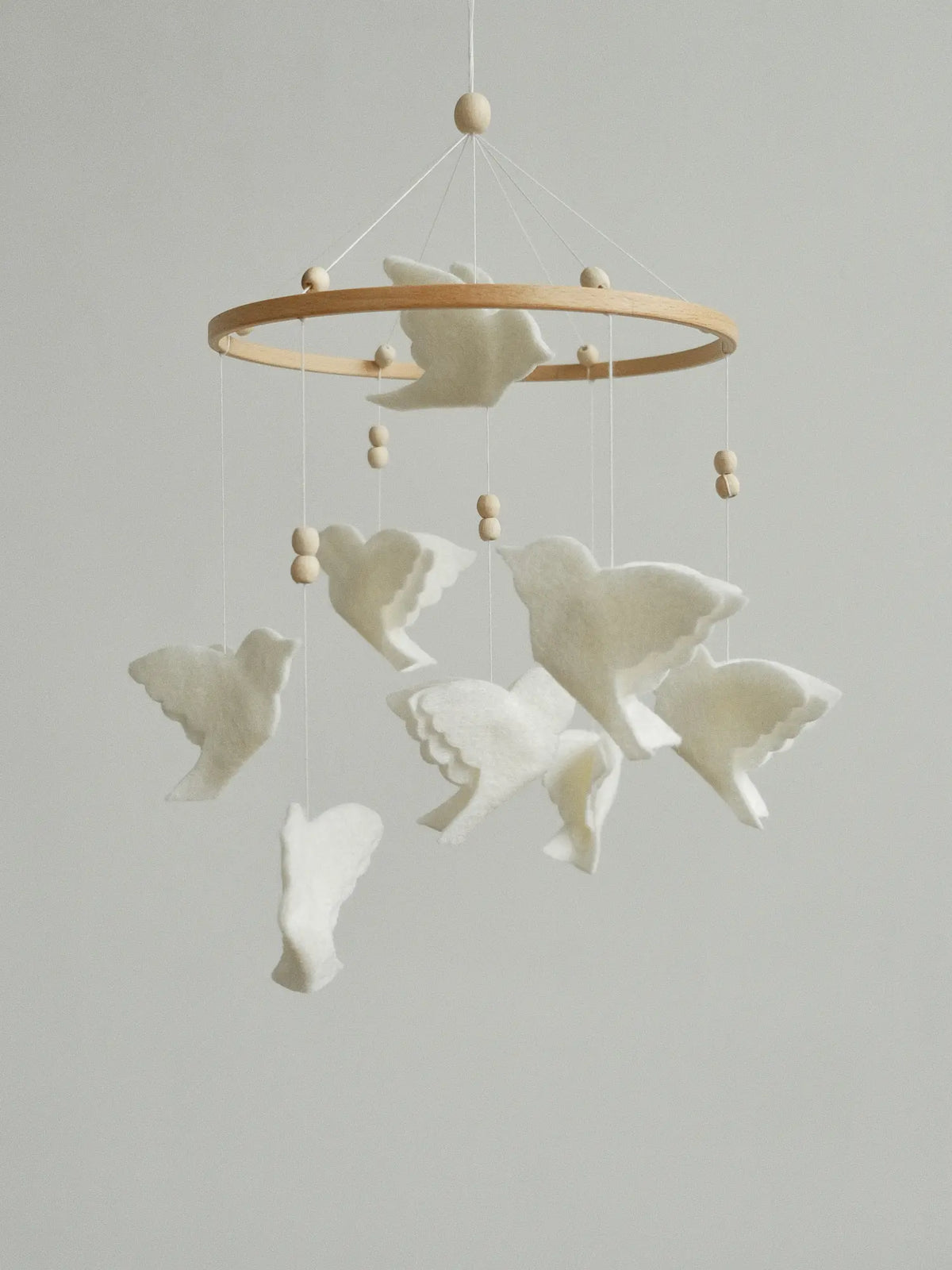 White felt animal mobile with layered flying birds, a natural wooden hoop and wood beads
