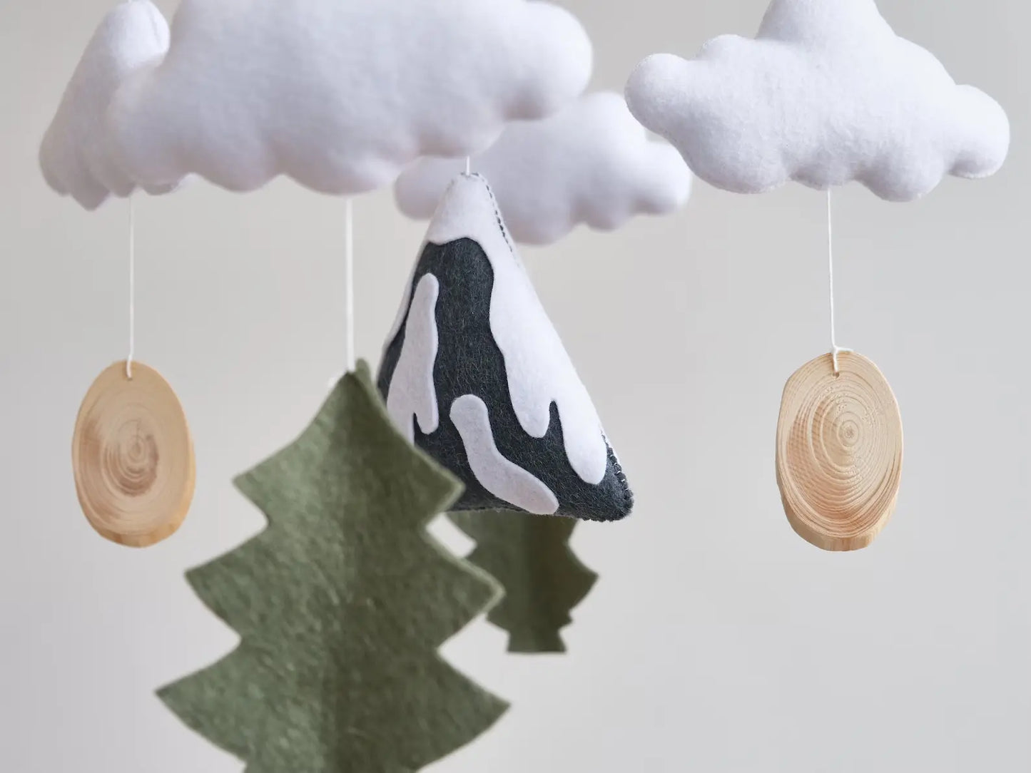 Felt mountain and fir tree closeup – snowy peak with wood slices on handmade baby mobile