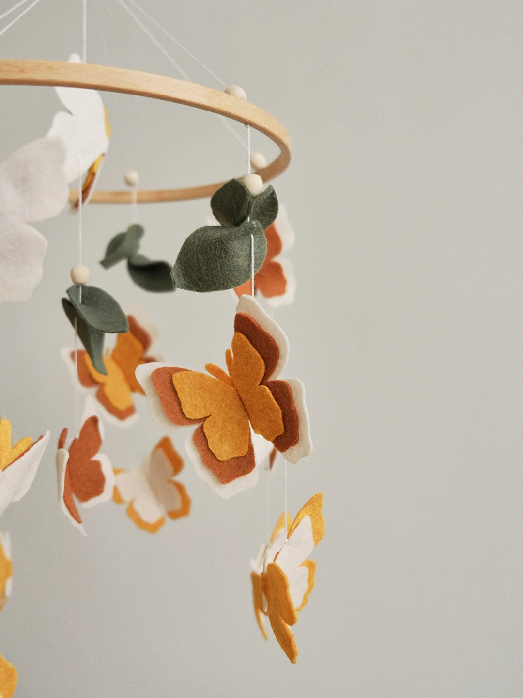 Felt neutral butterfly closeup – amber and terracotta layered wings on handmade baby mobile