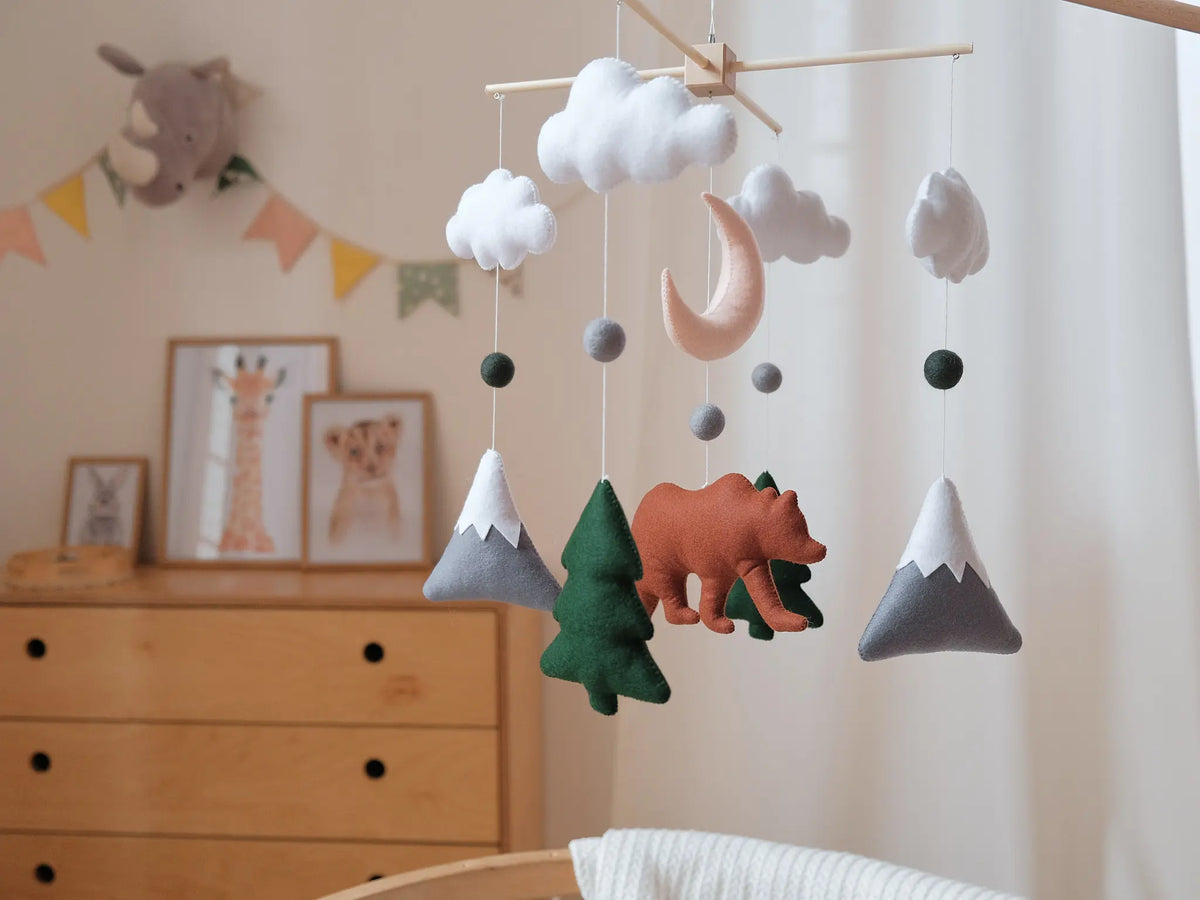 Handmade felt woodland mobile with bear, snowcapped mountains, moon and clouds in a forest nursery