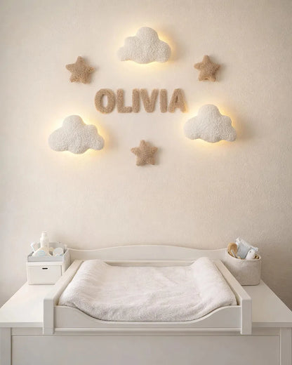 Nursery room with a changing table, decorative stars, and cloud lights on a light-colored wall.