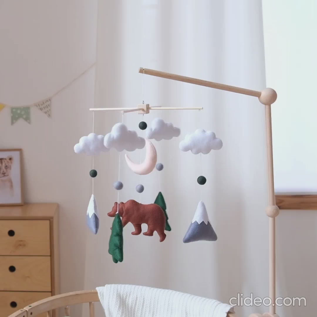 Handmade felt bear woodland baby mobile with mountains, moon, clouds and fir trees gently moving above a crib