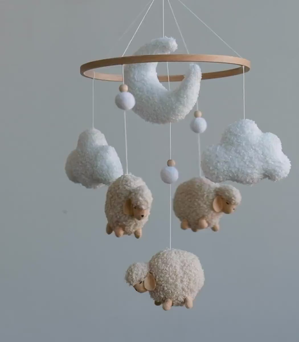 Handmade boucle sheep moon and cloud baby mobile slowly spinning above nursery crib