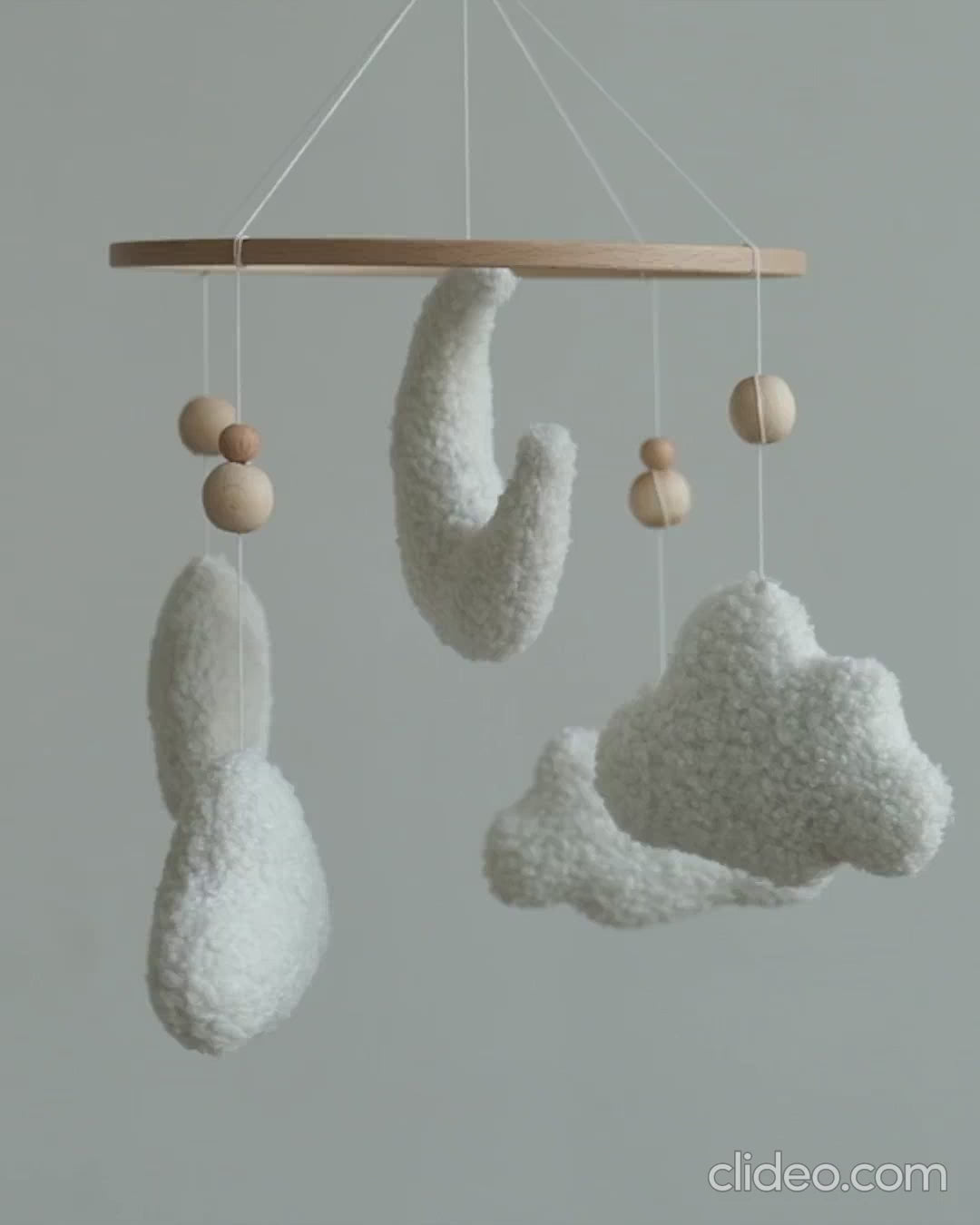 Handmade boucle baby mobile with moon and clouds gently spinning above nursery crib