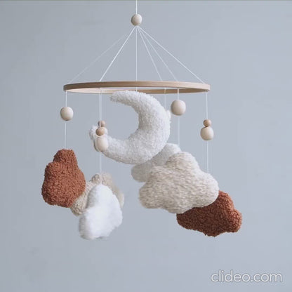 Handmade boucle baby mobile with terracotta and cream clouds spinning above crib