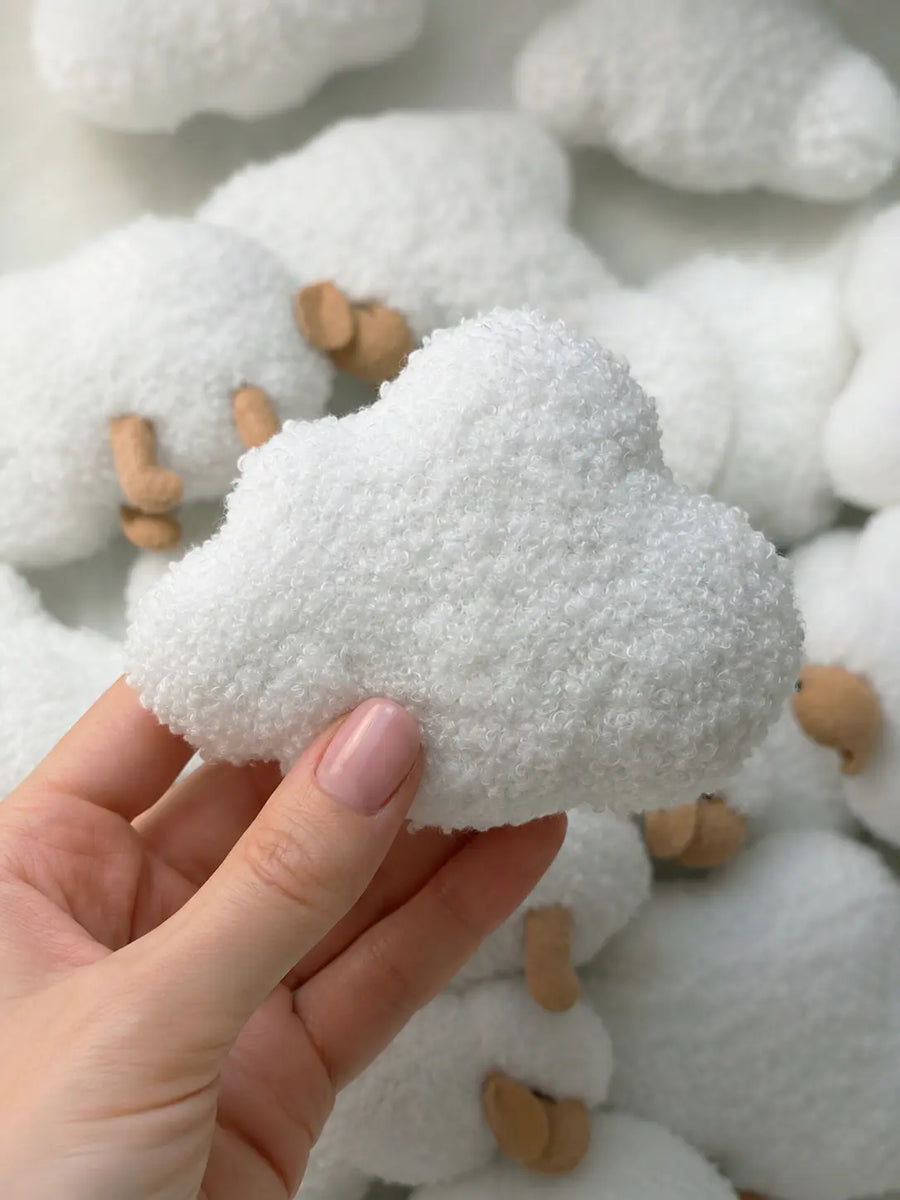 Handmade boucle cloud close-up for soft baby mobile with plush sheep in background