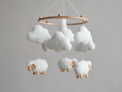 Hand holding white boucle cloud from soft baby mobile with sheep and clouds in background