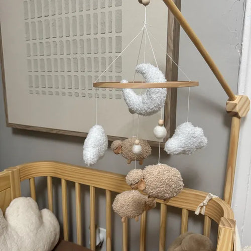 Customer review photo of a white boucle moon and cloud mobile hanging from a wooden crib arm