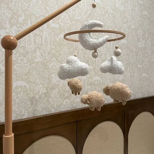 Customer photo of a boucle sheep, cloud and moon crib mobile in a neutral patterned nursery
