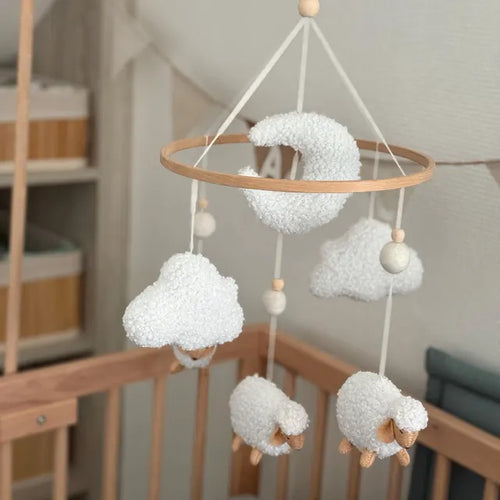 Customer review photo of a soft boucle mobile with white sheep, clouds and moon above a wooden crib