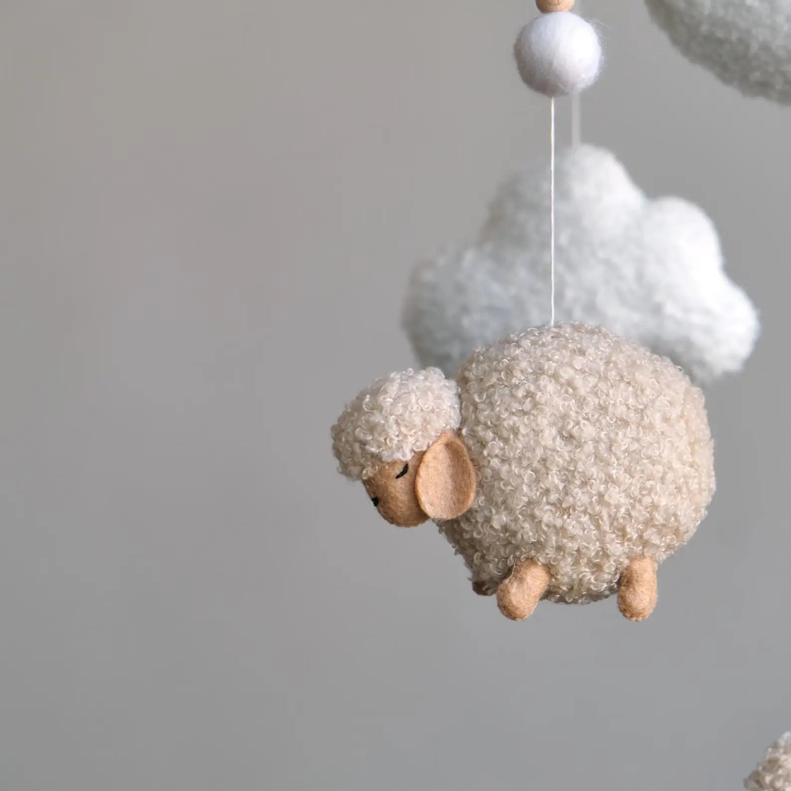 Close-up of handmade boucle sheep figure for baby mobile showing plush detail and felt face