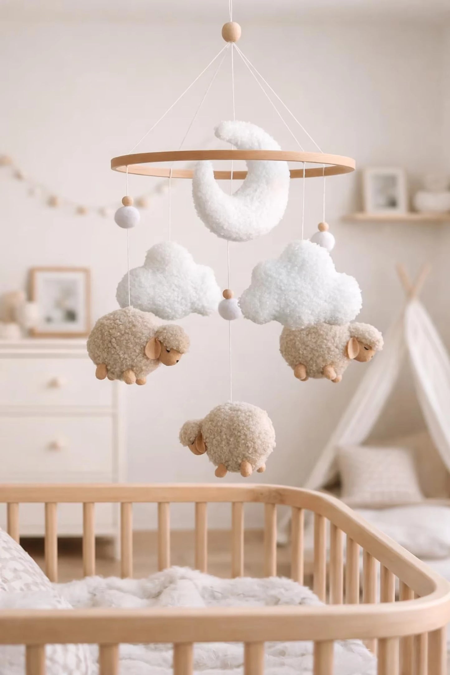 Boucle sheep and cloud baby mobile hanging above wooden crib in neutral nursery