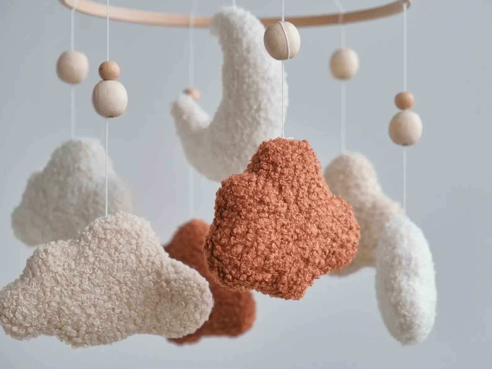 Close-up of boucle fabric texture on terracotta cream and beige cloud mobile