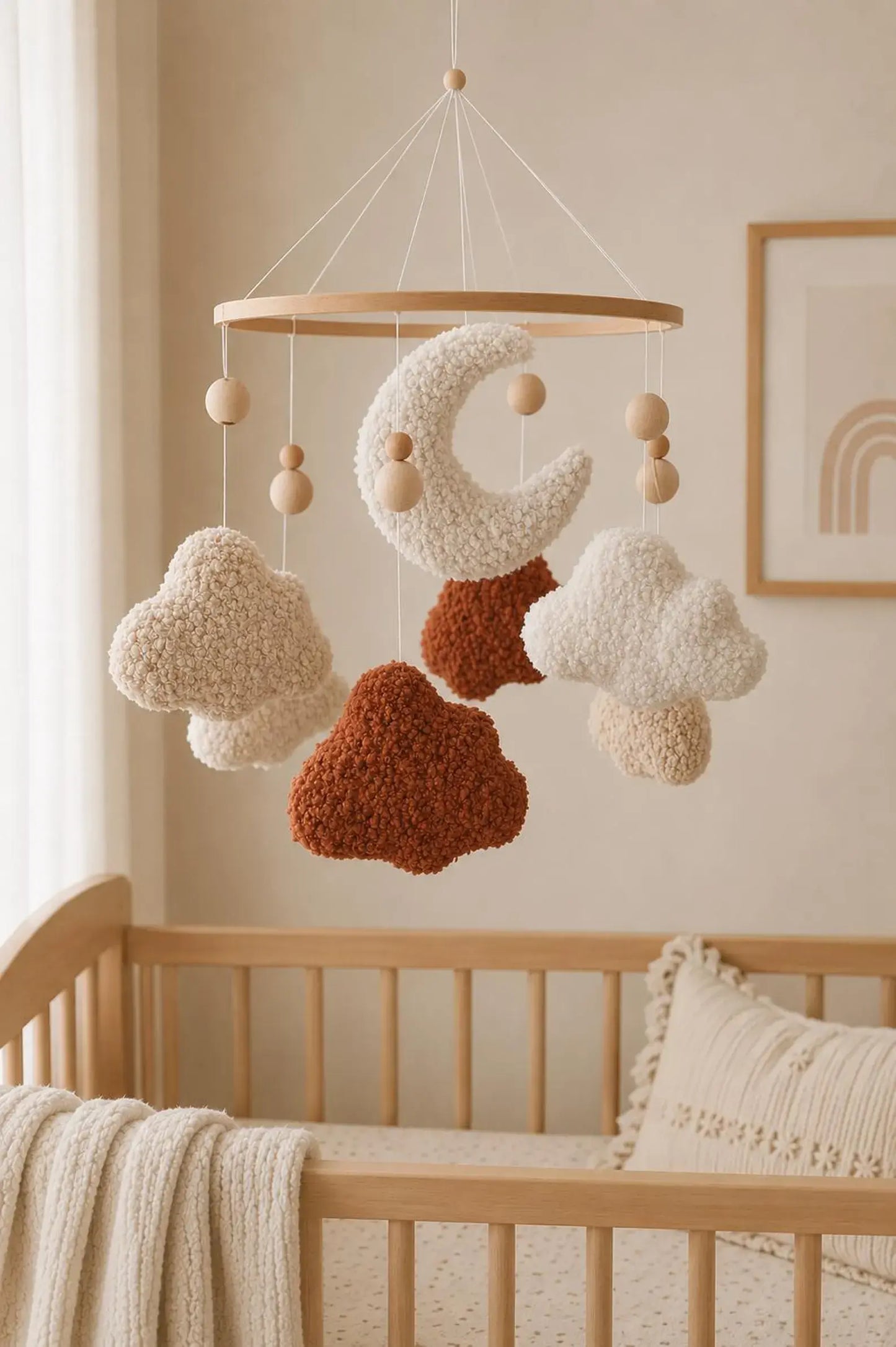 Terracotta and cream boucle moon cloud mobile over wooden crib in earthy nursery decor